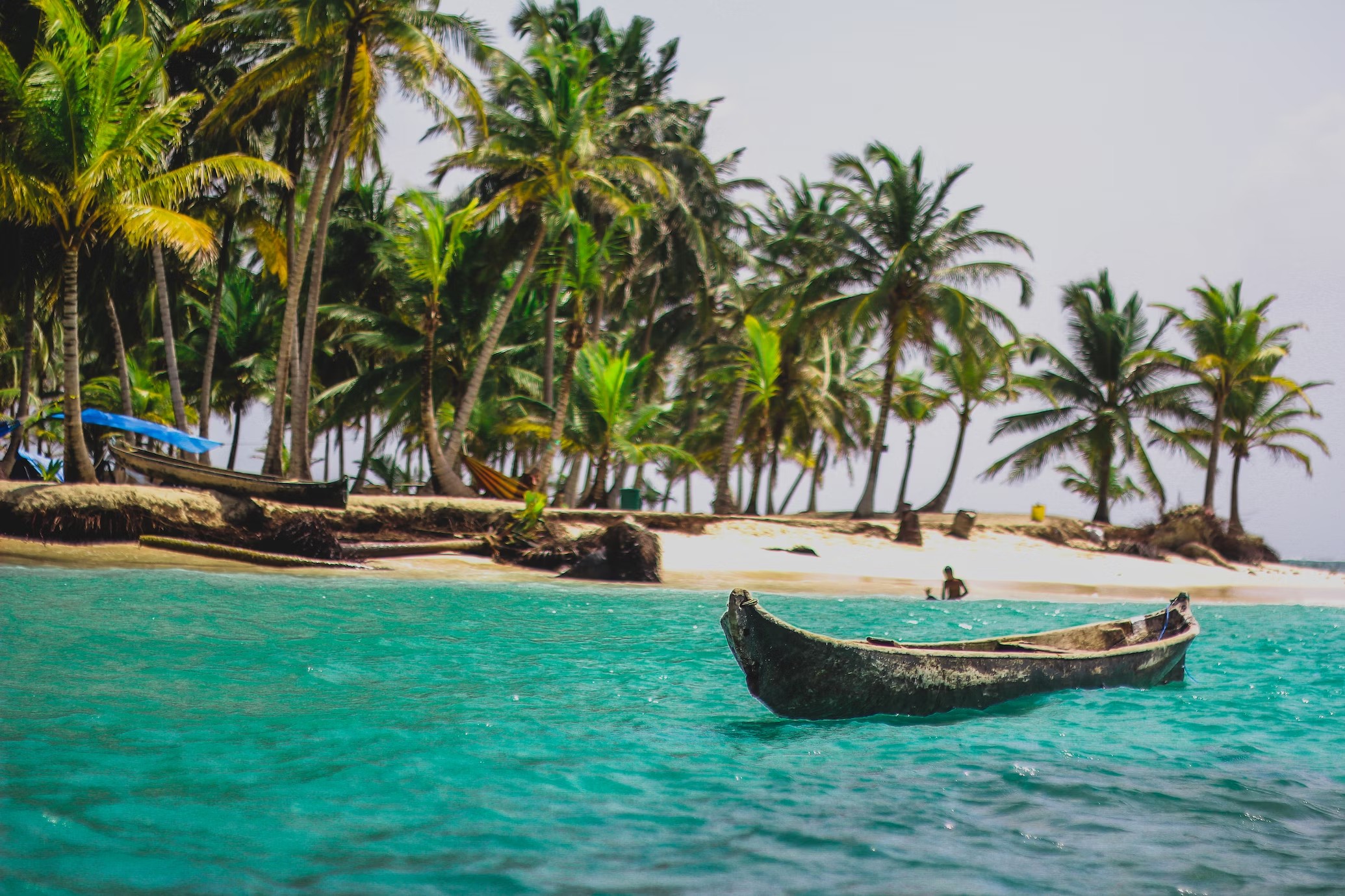 Rondreis Panama, San Blas eilanden, boot in water met strand en palmbomen