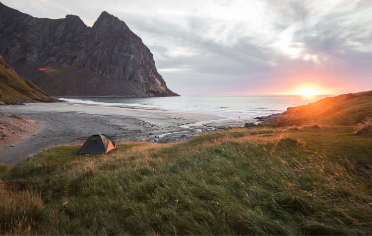 Campingplek aan zee op het strand met zonsondergang