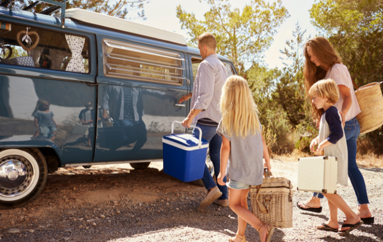 Camper met kinderen. Gezin met kinderen bij een camper. Mandjes met eten en drinken mee