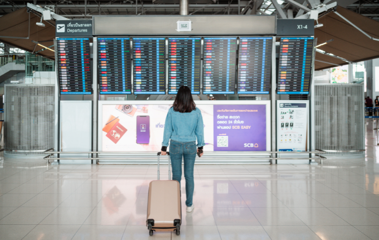 Vrouw kijkend naar vlucht informatie in de vertrekhal van de luchthaven
