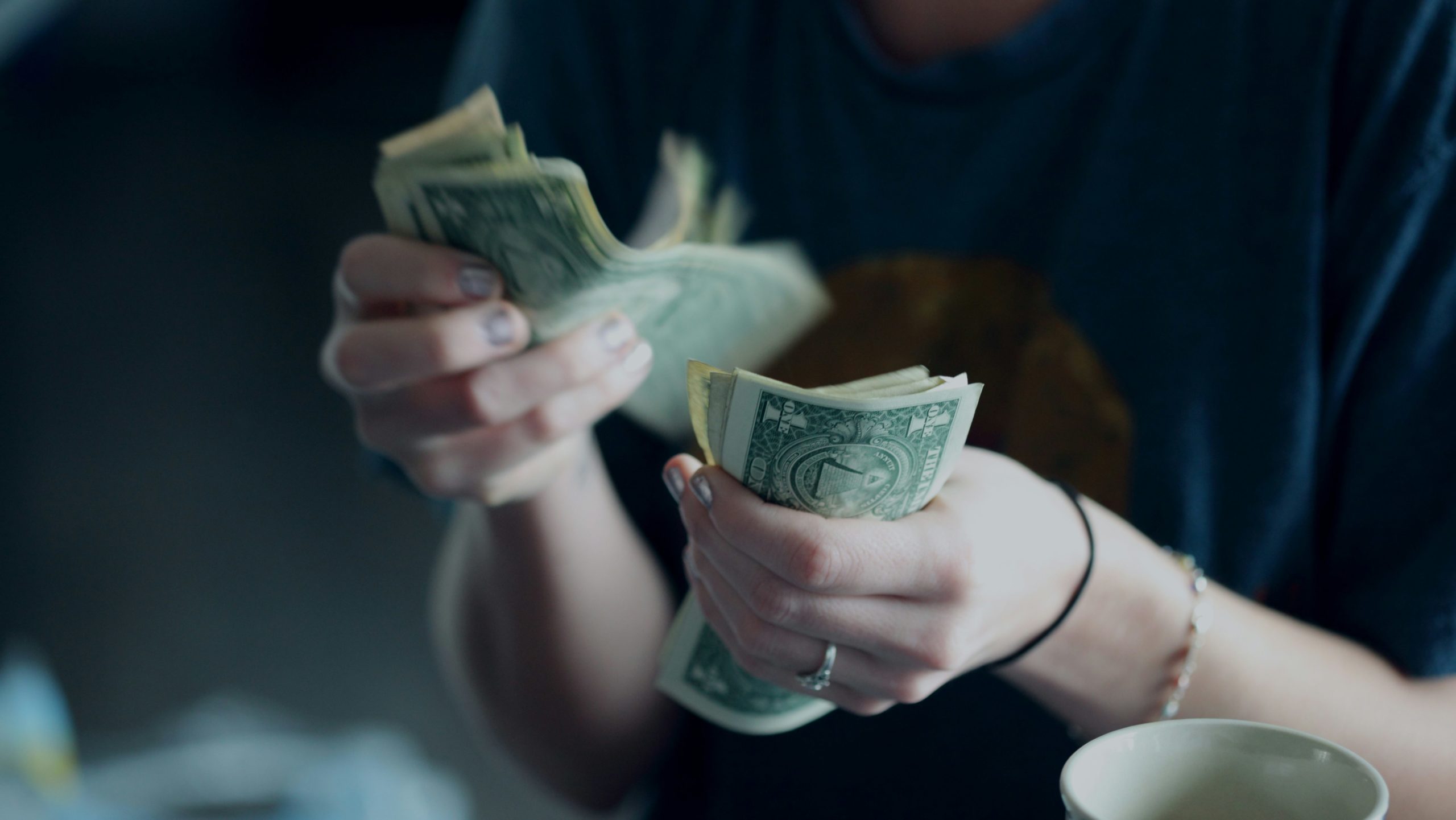 Twee handen met briefjes geld erin met donkere achtergrond