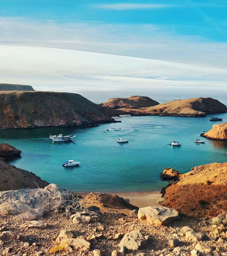 Rondreis Oman, Bandar Al Khairan. baai met boten en heuvels