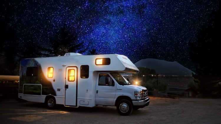 Camper bij sterrennacht in het donker