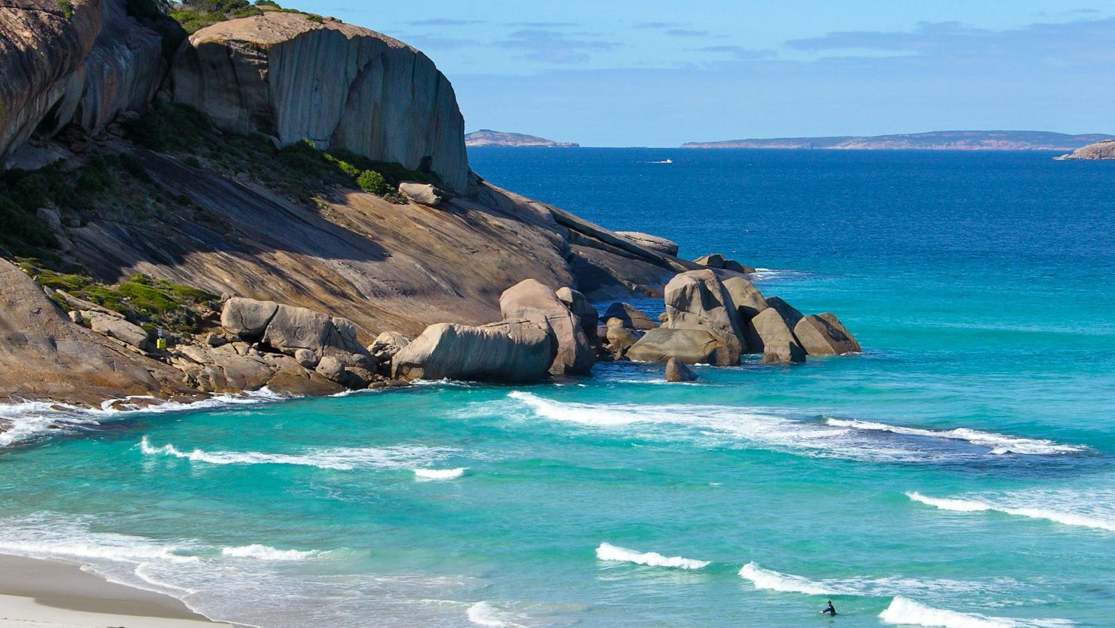 Rondreis Australië, Esperance, Strand met rotsen en surfer in het water
