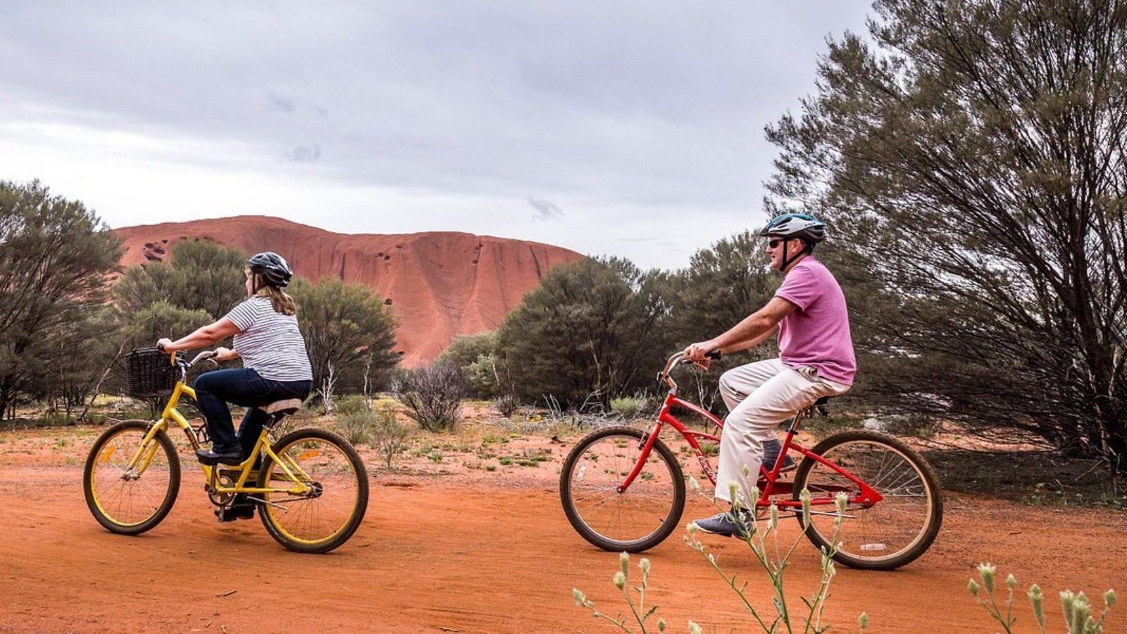 Rondreis Australië, Ayers Rock, Excursie Fietsen rond Uluru, Twee fietsende mensen bij Uluru rots